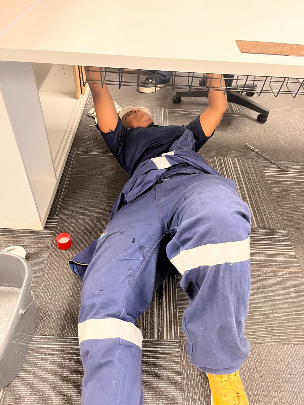 Worker kneeling to clean underneath a desk